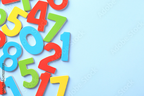 Colorful numbers on light blue background, flat lay. Space for text