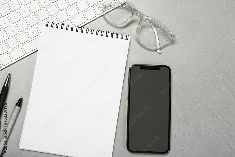 Naklejka premium Flat lay composition with open notebook and smartphone on light grey table