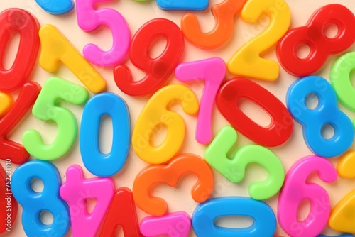 Colorful numbers on beige background, top view