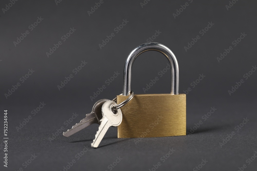 Steel padlock with keys on dark grey background, closeup Steel padlock with keys on dark grey background, closeup