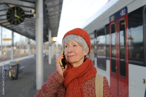 Senior woman talking on the phone at train station platform