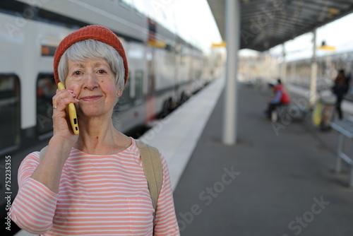 Senior woman talking on the phone at train station platform 