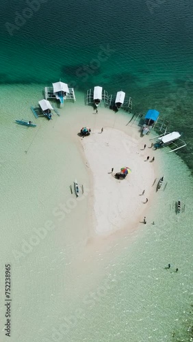 White sandbar with turquoise water and waves. Boats floating on coastline. Surigao del Sur. Philippines. Vertical view. photo