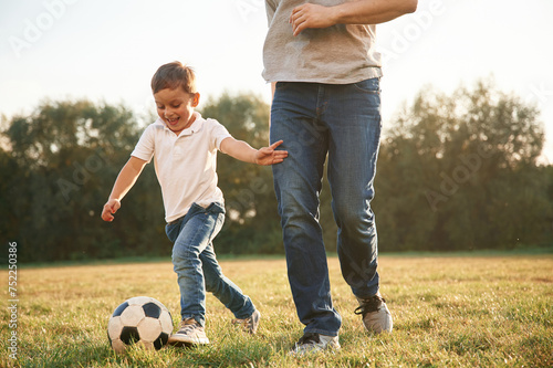 Playing soccer. Father and little son are having fun outdoors #752250386