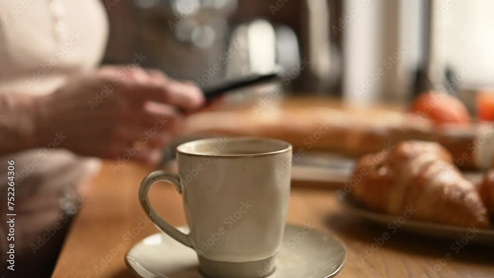 Girl chatting at smartphone and drink morning coffee cappuccino from cup. Woman with creamy espresso and mobile phone at kitchen Girl chatting at smartphone and drink morning coffee cappuccino from cup. Woman with creamy espresso and mobile phone at kitchen