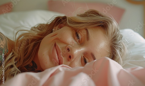 European woman lying in bed, just woken up, looking sleepily at the camera photo