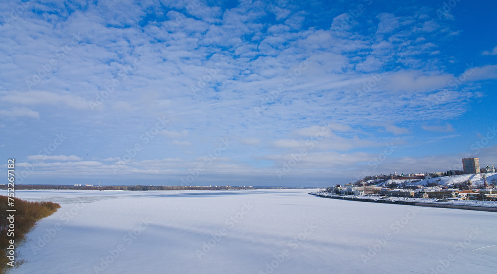 Panoramic view of the city and the snow-covered, frozen river. Winter landscape with a view of a large river in ice and snow.