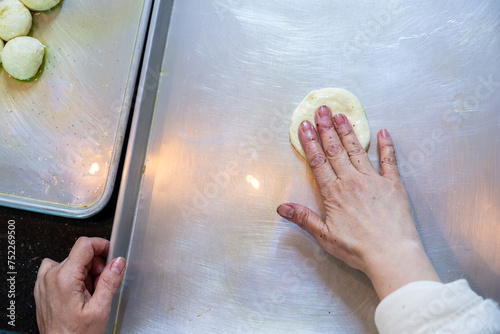 Female hands flattening dough balls and shaping it in circles to be stuffed later, dough hand made photo