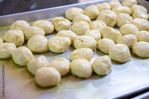 Dough balls on metal tray with olive oil to make sure it is not sticking and can be shaped later to be used and stuffed