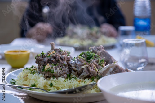 hot fresh mansaf steam with hands around it ready to be eaten on family table for iftar photo