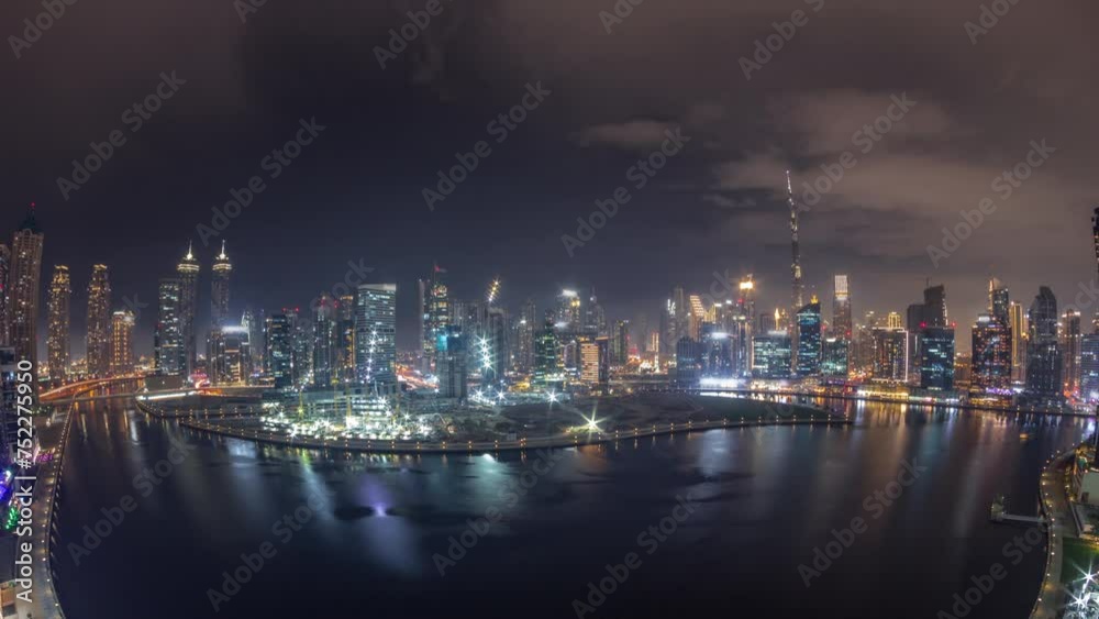 Aerial view to Dubai Business Bay and Downtown with the panoramic skyline skyscrapers and towers along waterfront on canal day to night transition timelapse. Construction site with cranes after sunset Aerial view to Dubai Business Bay and Downtown with the panoramic skyline skyscrapers and towers along waterfront on canal day to night transition timelapse. Construction site with cranes after sunset