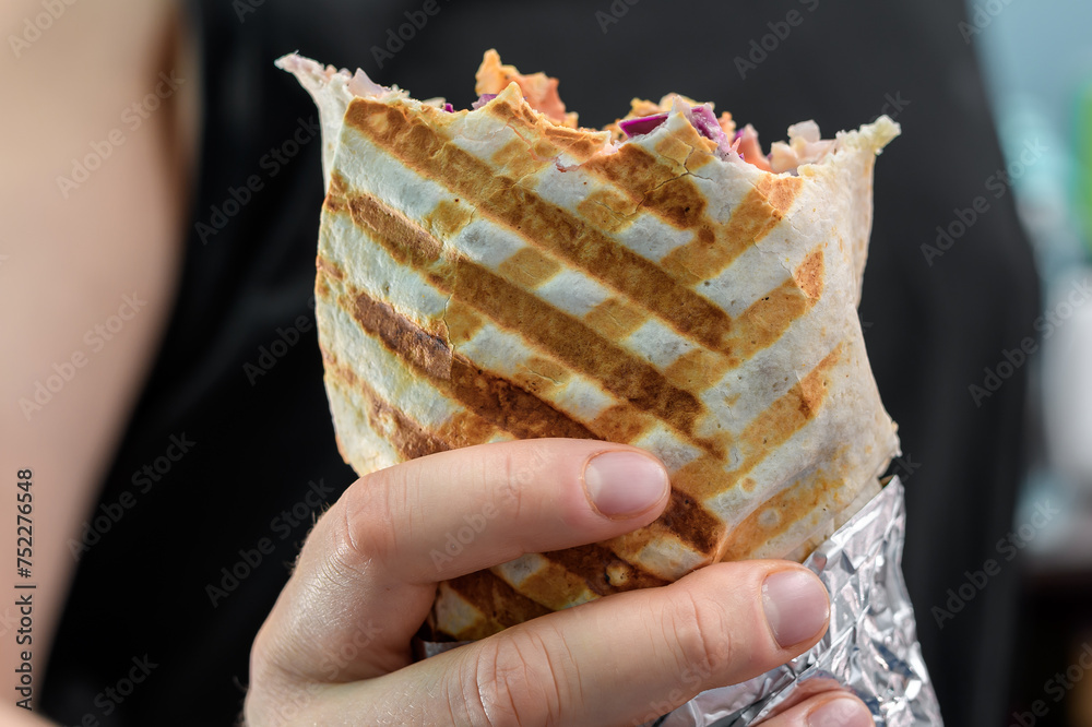 Fototapeta premium Kebab zwinięty w tortillę opiekany na grillu trzymany w dloni