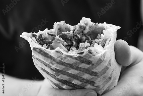Niezdrowe rakotwórcze jedzenie, tłusty kebab fast food w dłoni czarno-białe zdjecie