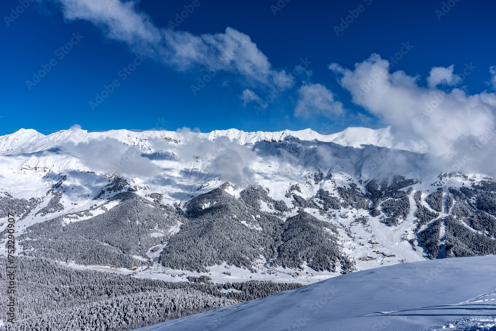 Beautiful landscape of the Arkhyz ski resort with mountains, snow, forest on sunny winter day. Caucasus Mountains, Russia.