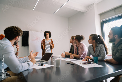 Smiling diverse colleagues gather in boardroom brainstorm discuss financial statistics together