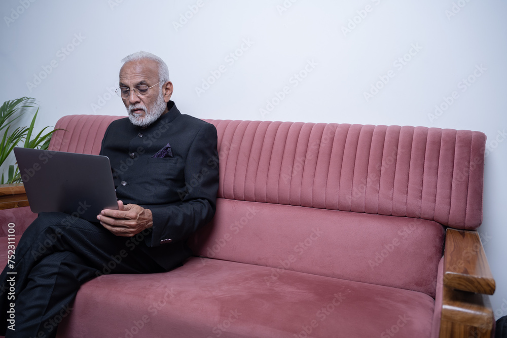 Portrait of mature Indian or Latin business man ceo trader using laptop computer, typing, working from home