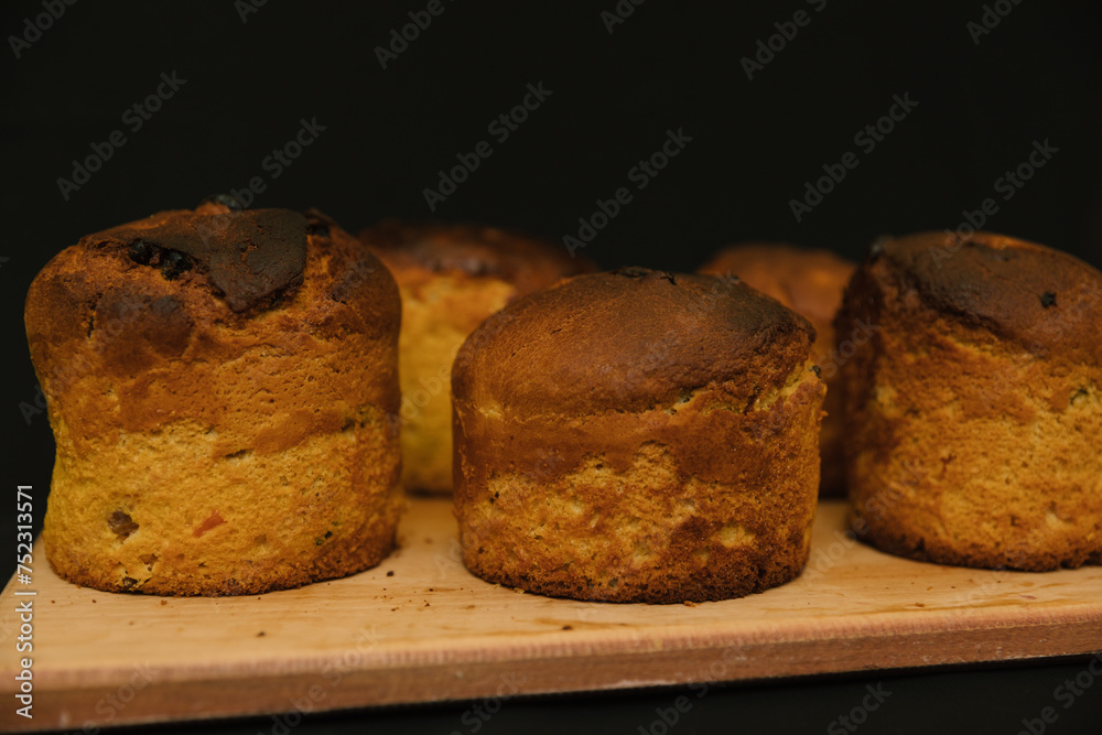 Freshly Easter cakes without decorations on a wooden board on a black background. Easter cakes cools down. Freshly Easter cakes without decorations on a wooden board on a black background. Easter cakes cools down.