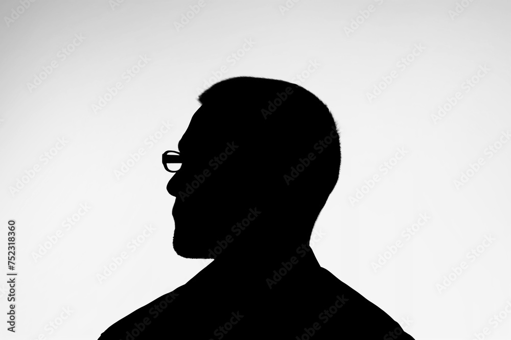 Silhouette of dark person profile on light background.