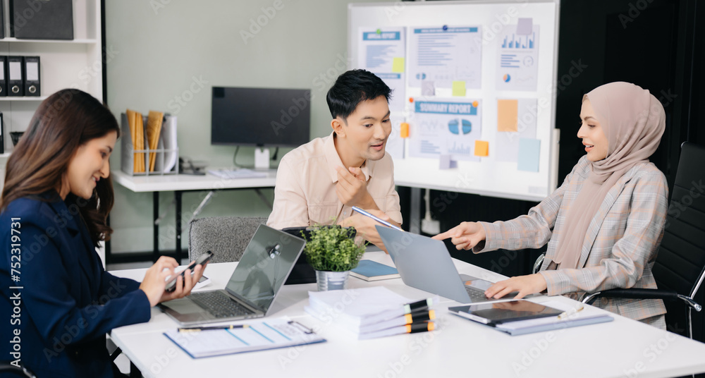 Happy businesspeople while collaborating on a new project in an office. Group of diverse businesspeople using a laptop and tablet Happy businesspeople while collaborating on a new project in an office. Group of diverse businesspeople using a laptop and tablet