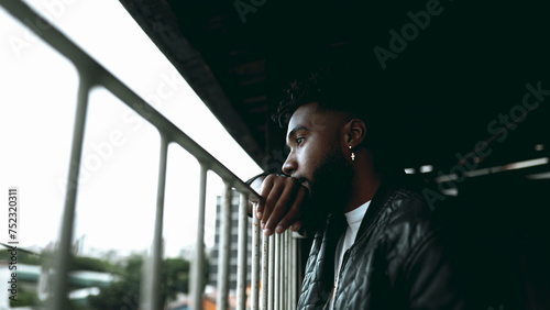Tableau sur toile One Pensive Young Black Man in 20s Leaning on Balcony, Deep in Thought