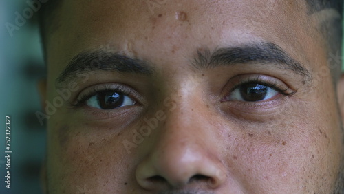 One serious young black latin hispanic man close-up eyes staring at camera with solemn expression. South American Brazilian person eye to eye stare