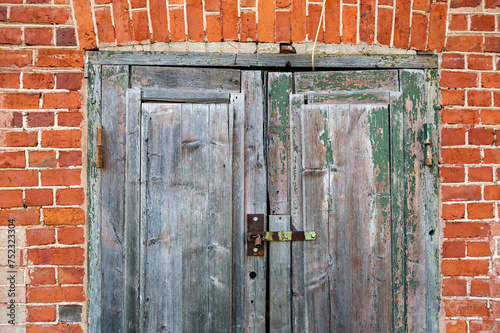 Old wooden door in front of a red brick wall