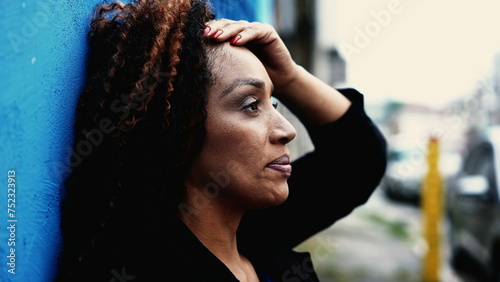 Quadro su tela One Stressed South American black woman struggling with anxiety and worry while leaning on urban wall outside in city street