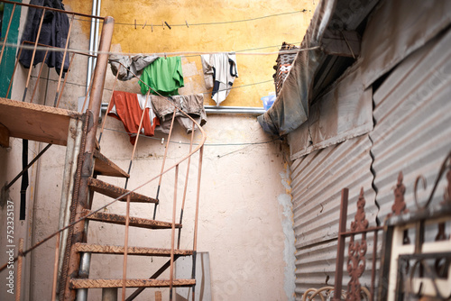 Fototapeta Naklejka Na Ścianę i Meble -  Stairs, outdoor and steel house with rust in zinc material with garbage at informal settlement or neighborhood in Brazil. Home, residential area and community with old or slum building in urban place