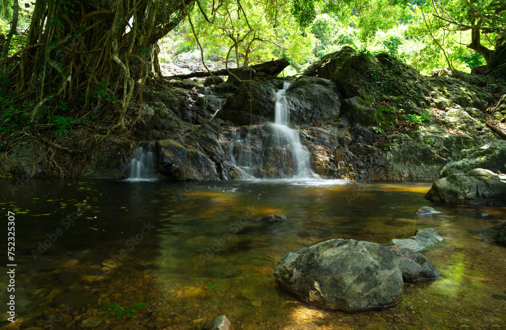 The rock is in the middle of the stream within the area of Sarika Waterfall. Khao Yai National Park Nakhon Nayok Province, Thailand has a small waterfall in the background. Blurry looks beautiful The rock is in the middle of the stream within the area of Sarika Waterfall. Khao Yai National Park Nakhon Nayok Province, Thailand has a small waterfall in the background. Blurry looks beautiful