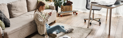 young teenager girl using her smartphone while sitting on carpet near the couch in living room
