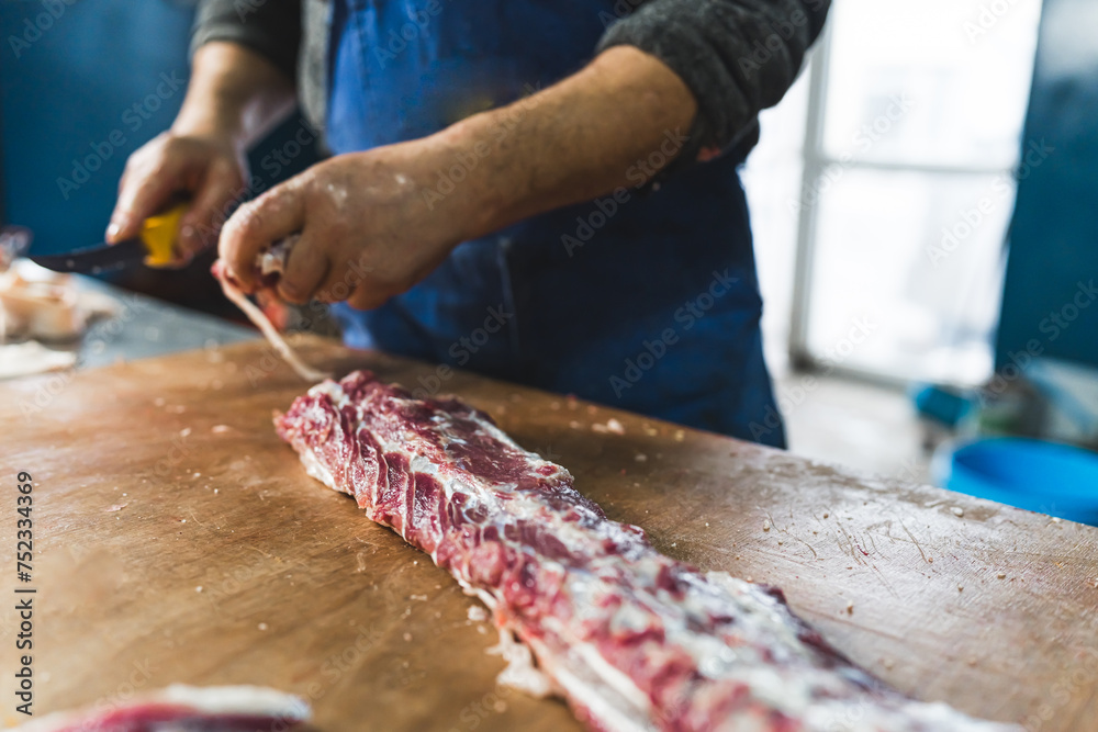 a butcher cutting pig ribs on the wooden table, closeup shot slaughterhouse. High quality photo
