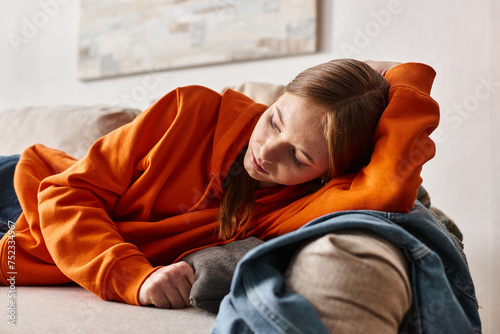 depressed gen z girl lying on sofa in living room, solitude and melancholy of teenager concept photo