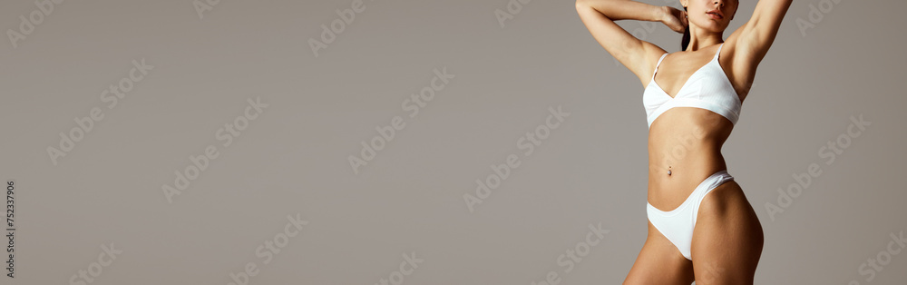 Banner. Slim and perfect female model posing in lingerie against grey studio background with negative space to insert text. Concept of beauty, spa procedures, dermatology treatments, cosmetology care.