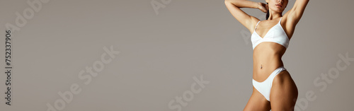 Banner. Slim and perfect female model posing in lingerie against grey studio background with negative space to insert text. Concept of beauty, spa procedures, dermatology treatments, cosmetology care.