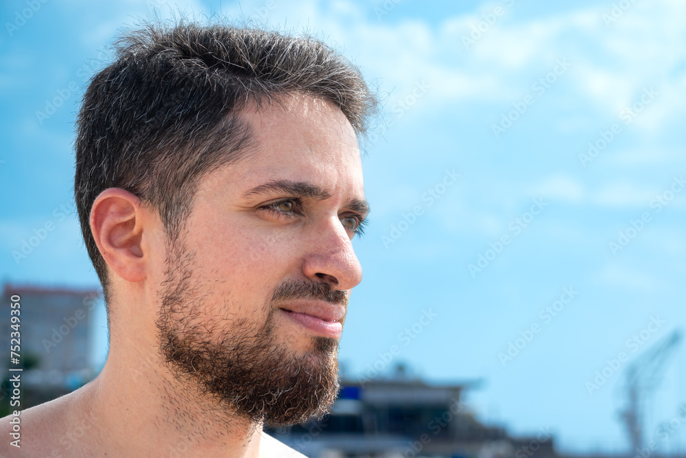 Obraz premium Close up of Young Hispanic man model looking horizon on beach posing sideways