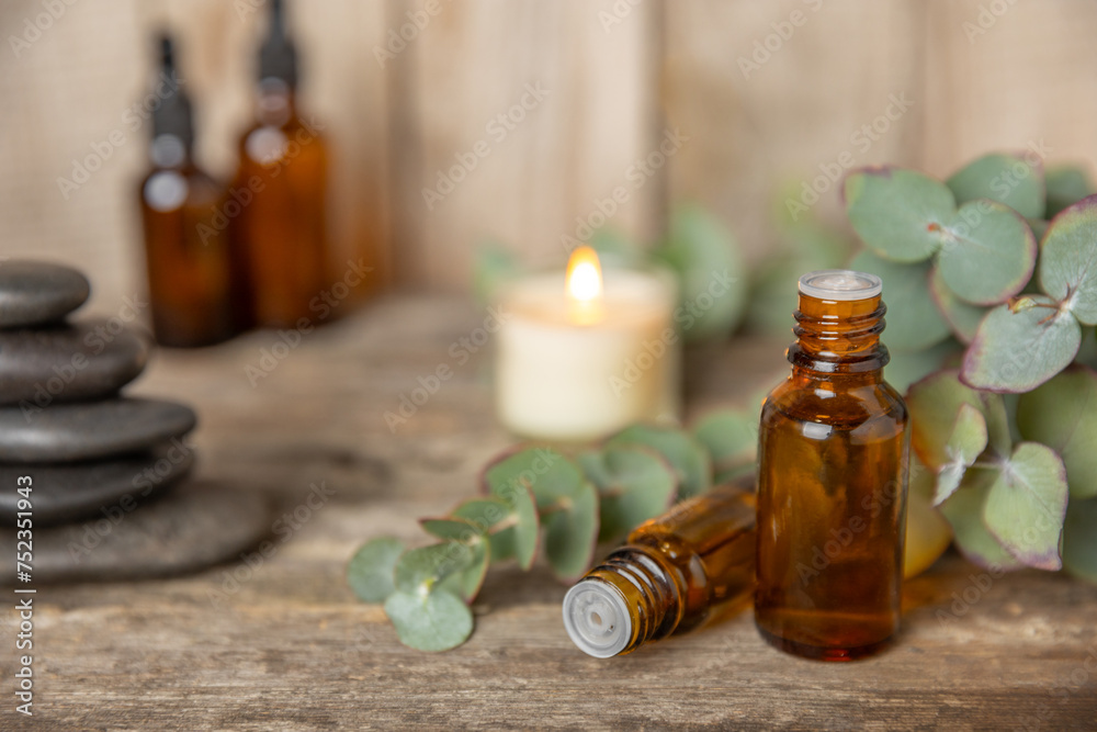 Eucalyptus essential oil in a glass bottle with green eucalyptus leaves on a textured wooden background. Aromatherapy concept. Spa. Natural organic ingredients for cosmetics and body care.Copy space Eucalyptus essential oil in a glass bottle with green eucalyptus leaves on a textured wooden background. Aromatherapy concept. Spa. Natural organic ingredients for cosmetics and body care.Copy space