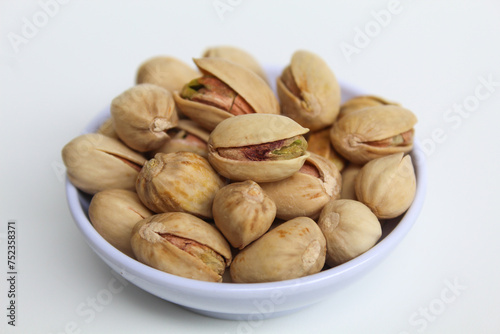 Salted pistachio on the small white bowl, isolated on white background
