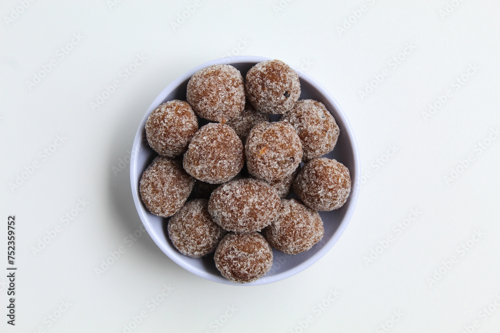 Tamarind candy balls in white bowl. Isolated on white background, flat lay or top view Tamarind candy balls in white bowl. Isolated on white background, flat lay or top view