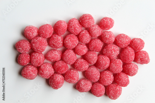 Soursop candy, in pink color and ball shaped, coated by sugar. On white background photo