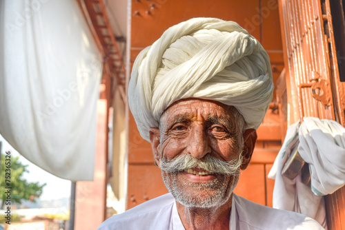 Elderly man with mustache and traditional Rajasthani turban smiling to camera