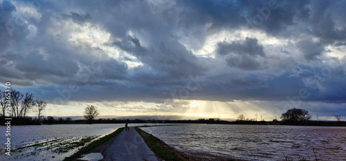 Kolenfeld wunstorf dirt road flooding with great cloudy sky and sunbeams germany