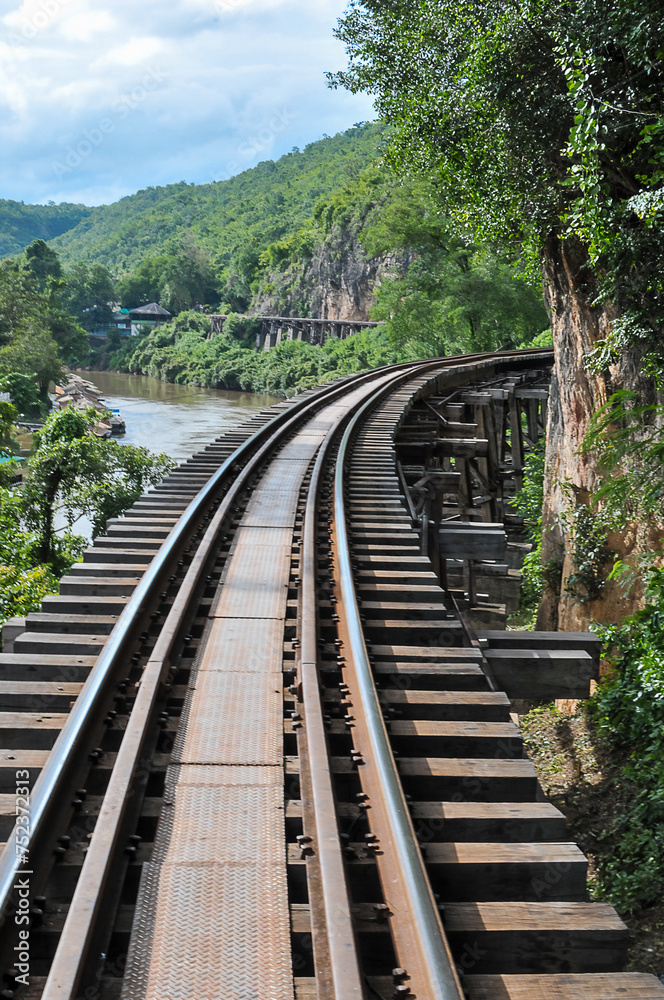 Tham Krasae Pass. A huge wooden trestle supports the tracks on a cliff bordered on one side by the mountain and on the other by the River Kwai