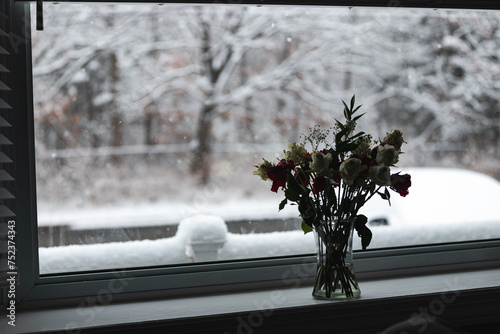 Bouquet of flowers in the window during a snowstorm 