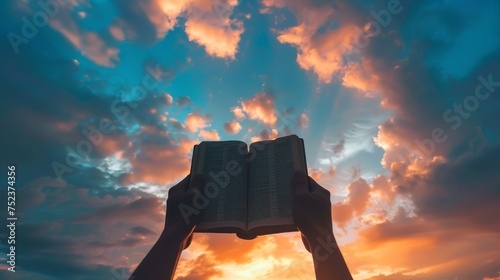 Silhouette of hands holding a Bible towards the sky