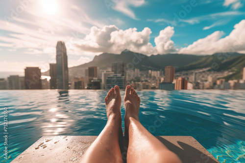 Feet dangling over edge of swimming pool with urban skyline in background