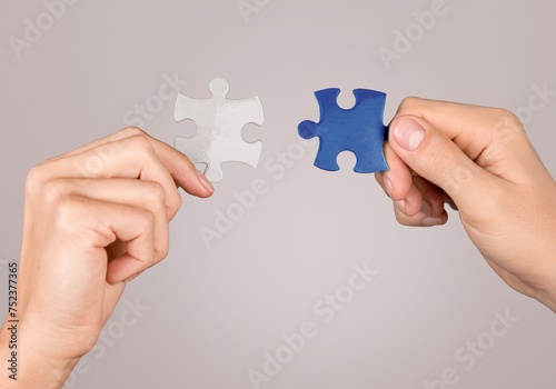 People hands connecting colored puzzles.