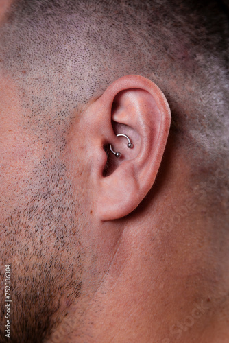 Outer ear black tragus piercing on adult white man