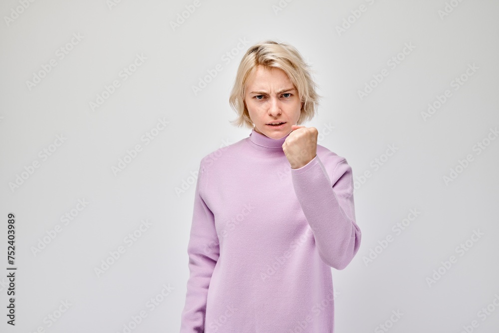 Angry woman in a purple sweater clenching her fists isolated on a white background. Angry woman in a purple sweater clenching her fists isolated on a white background.