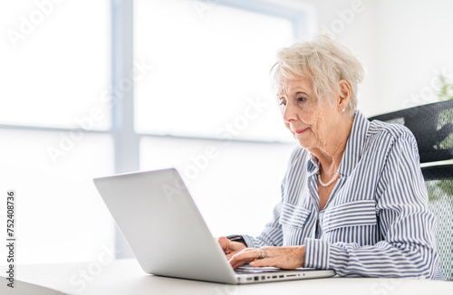 senior women using a laptop while sitting at the office