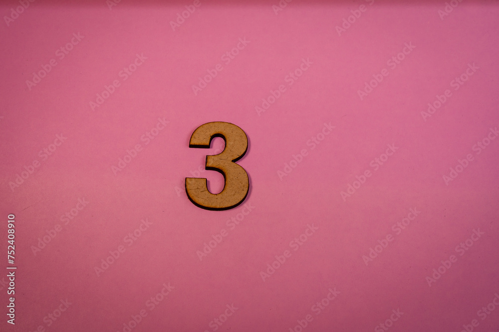 Number 3 in wood on a pink background Number 3 in wood on a pink background